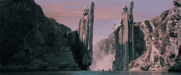The fellowship approach the mammoth staues of Argonath on a river in canoes.