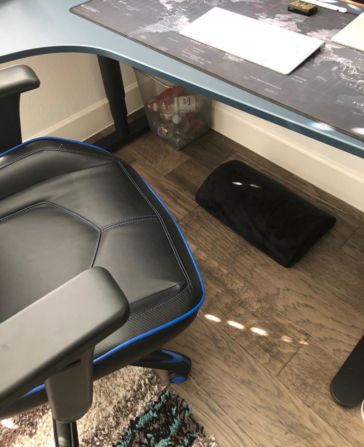 Reviewer pic of the footrest in black under a desk with an office chair in front of it