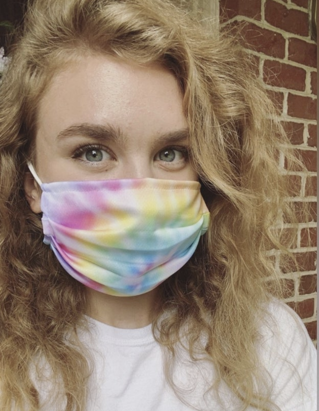 A BuzzFeed editor in a pastel tie dye rainbow mask