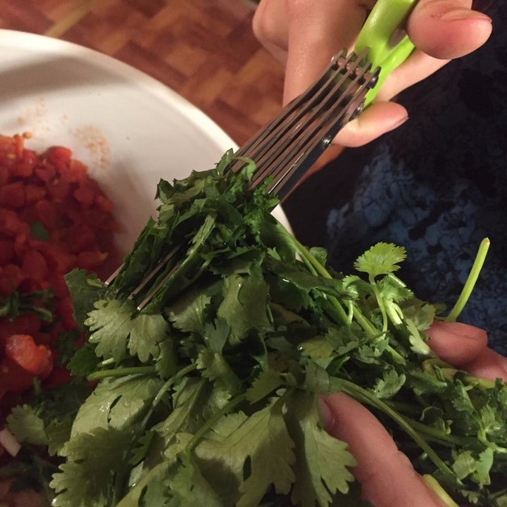 reviewer using the scissors to chop cilantro into a bowl