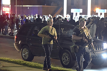 Kyle Rittenhouse and another militia member carrying assault rifles during a night of protest in Kenosha.