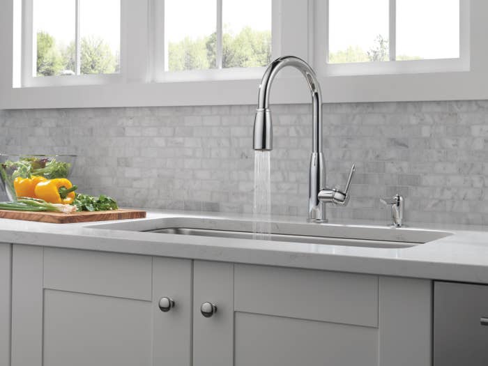 The faucet spraying into a kitchen sink