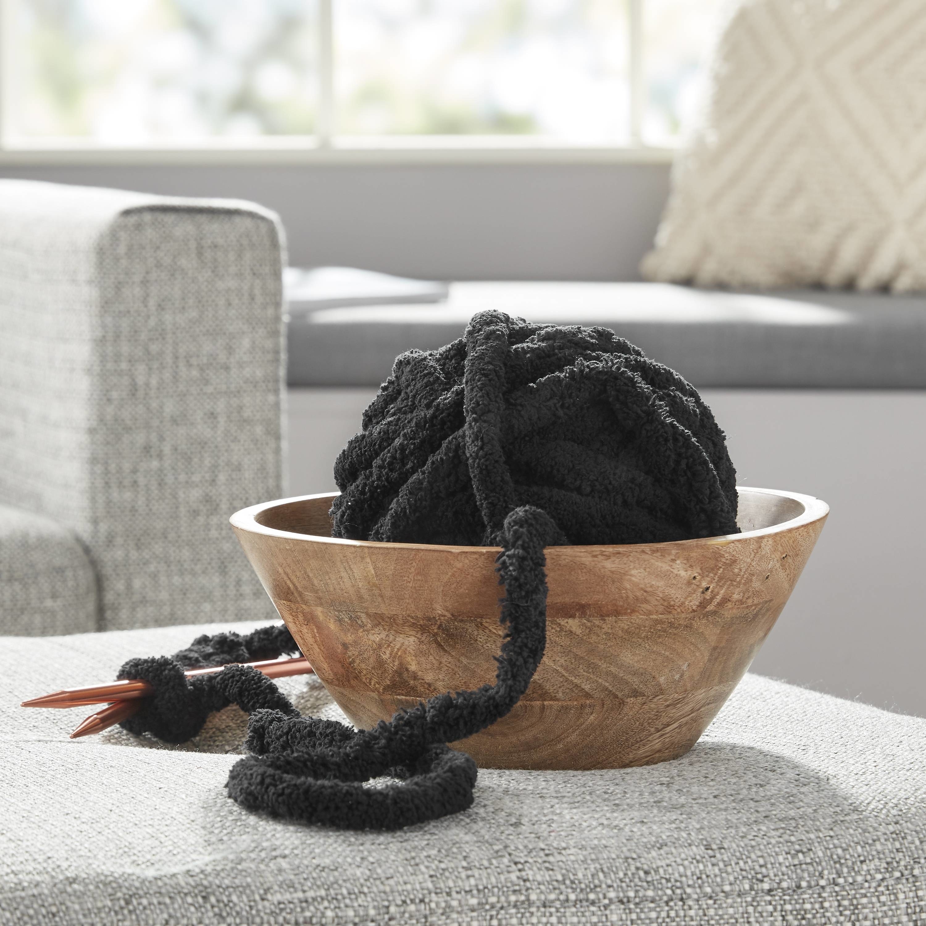 The black yarn in a wooden bowl