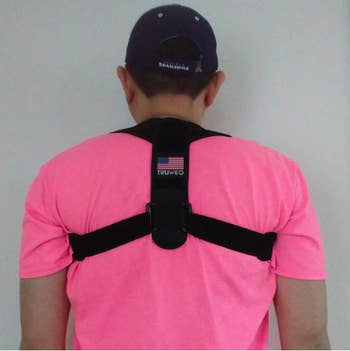 A reviewer wearing the black brace, which has a panel between your shoulder blade and straps for your arms