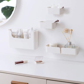 Four different sized shelves on the wall with assorted bathroom things in them