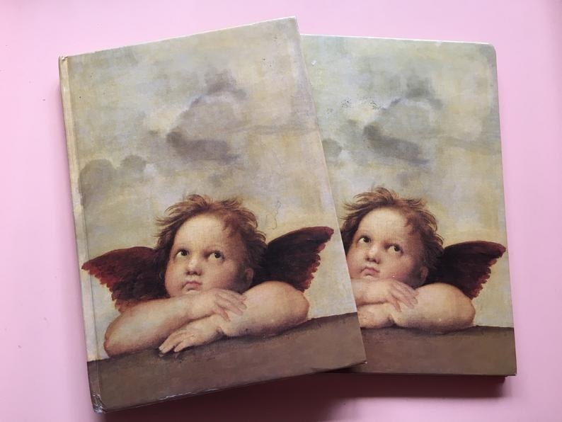 Two notebooks featuring one of the two cherubs of featured in Raphael&#x27;s Sistine &quot;Madonna&quot;