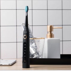 The electric toothbrush standing on an elegant and minimal bathroom vanity