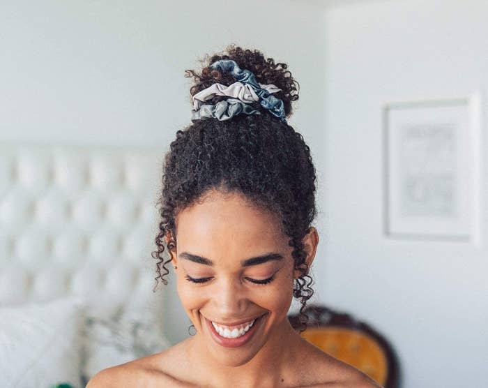 A smiling person wears the scrunchies in a high bun