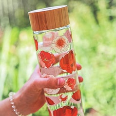 A close up of a person holding the glass water bottle