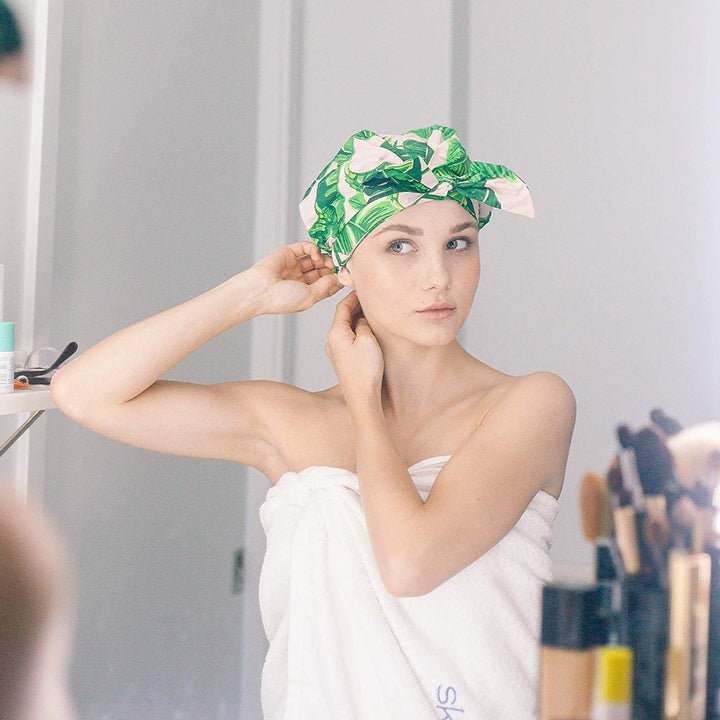 A person adjusts the shower cap in the mirror