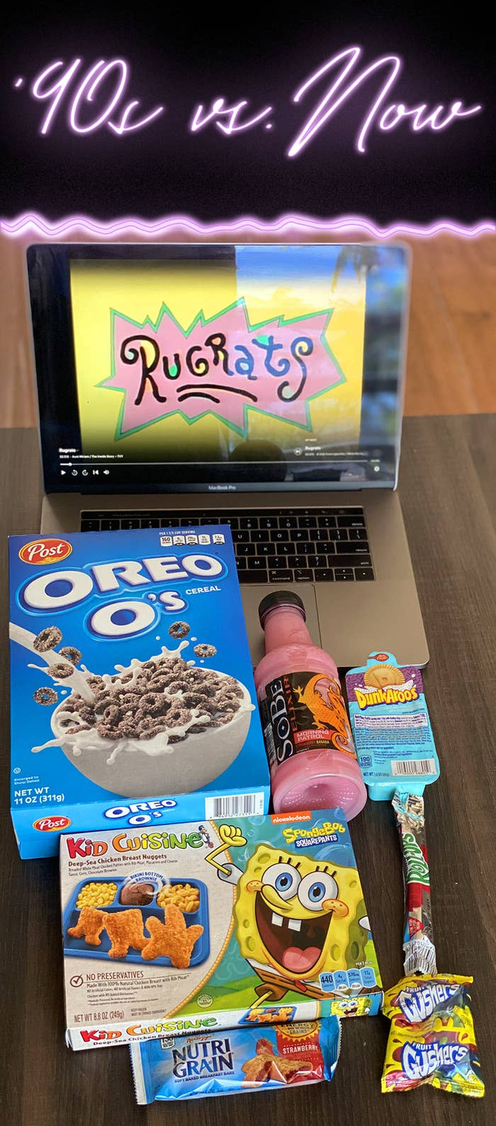 A laptop displaying Rugrats, a box of Oreo O&#x27;s cereal, a bottle of Strawberry banana SoBe, DunkAroos cookies, a Kid Cuisine frozen meal, a Fruit Roll-Up, a Nutri-Grain bar, and Fruit Gushers