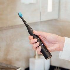 A person holds up the electric toothbrush