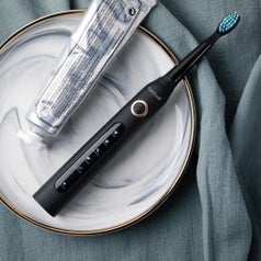 A flatlay of the toothbrush on a tray next to some toothpaste  