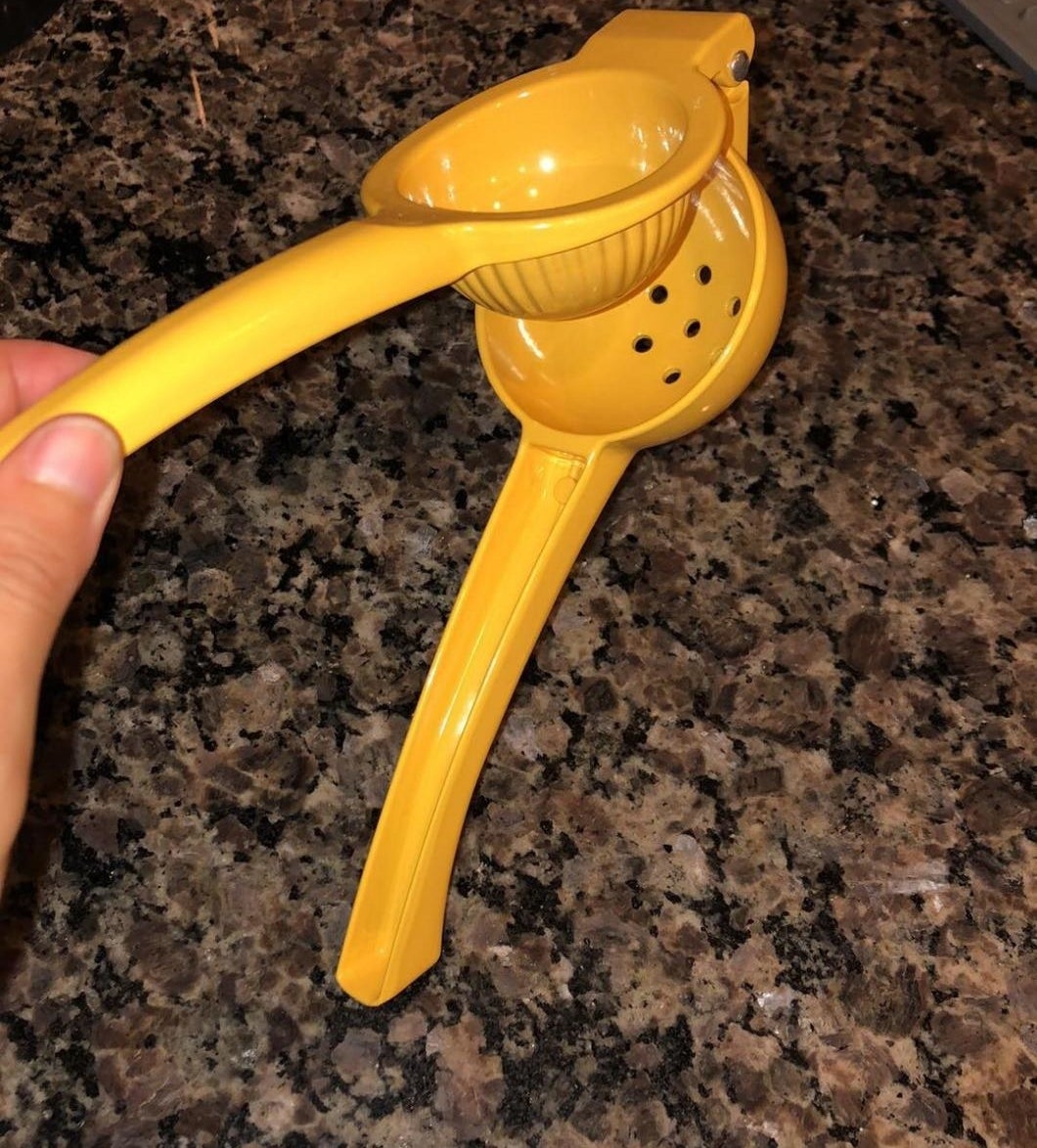 reviewer's yellow handheld citrus press