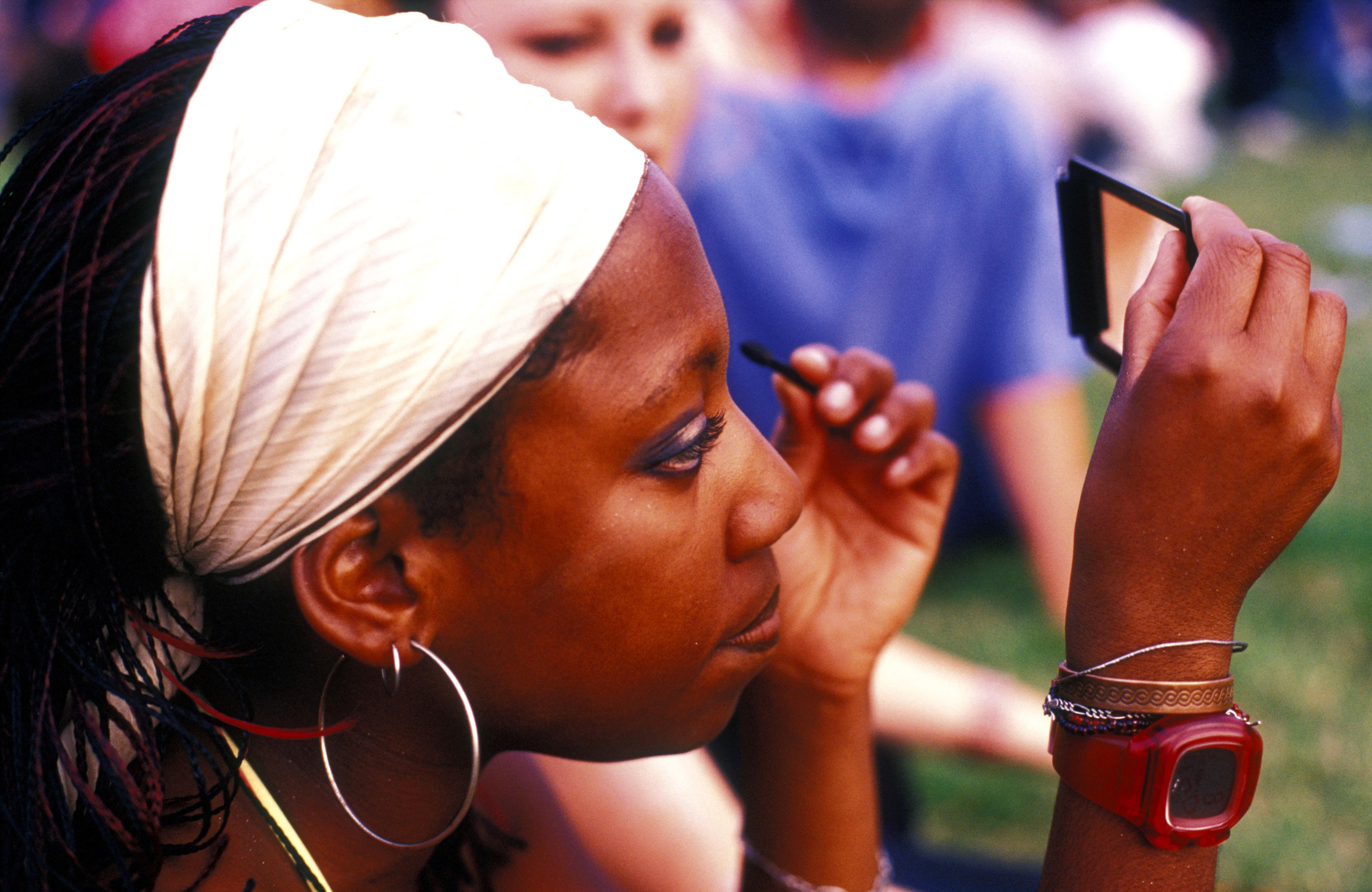 A photo of a woman holding a compact mirror while applying the eyeshadow 