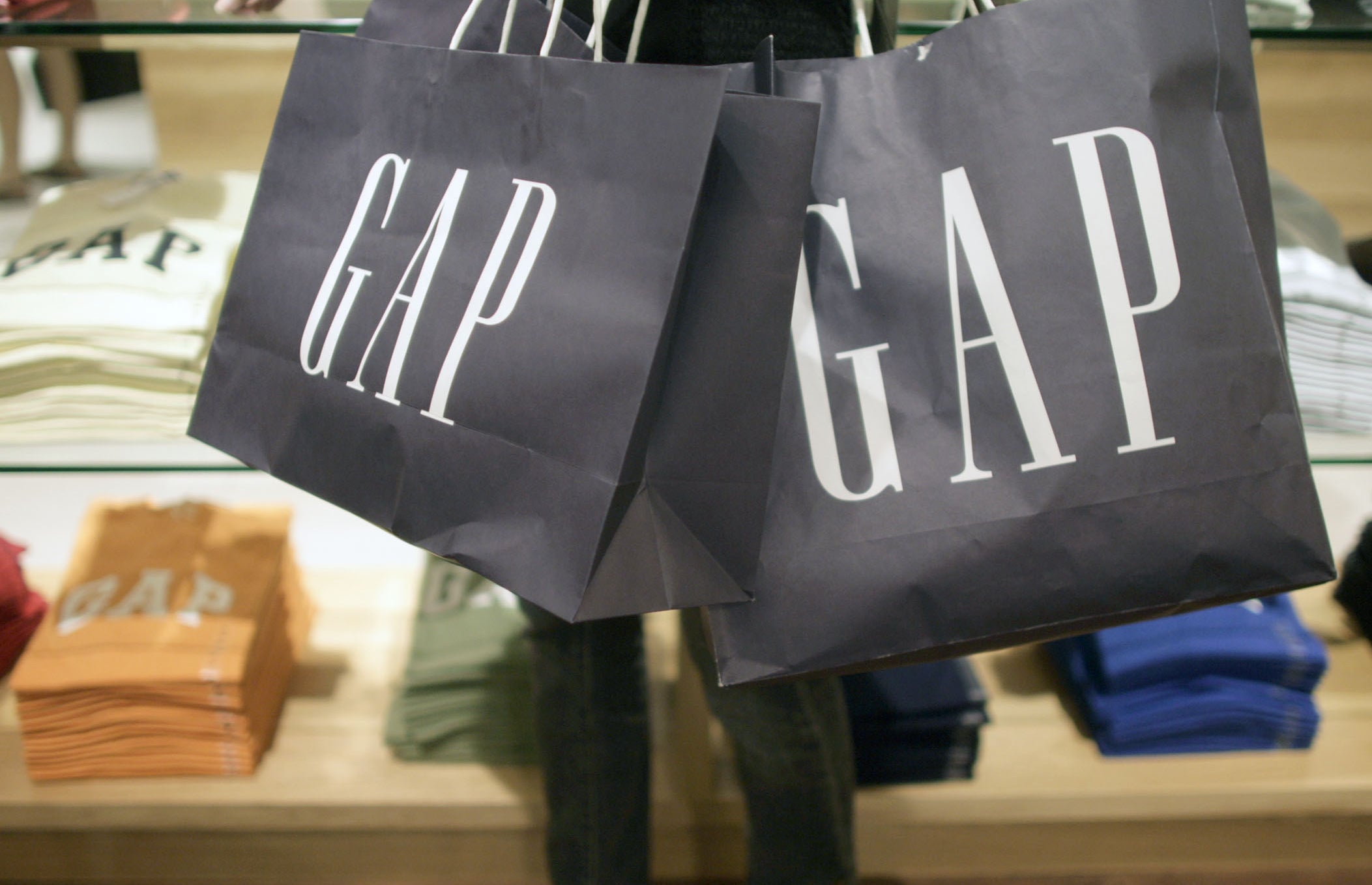A arm holding three navy blue GAP paper bags