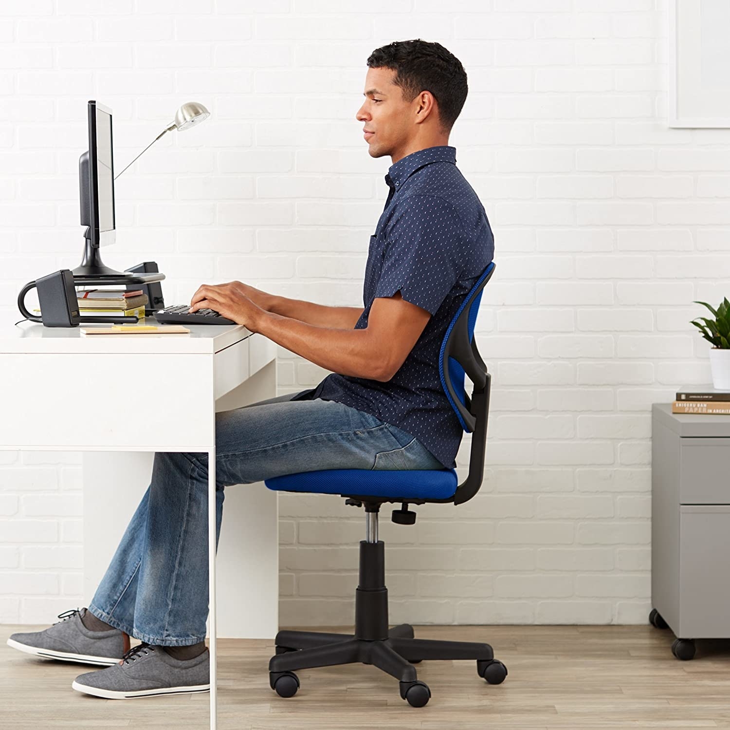 A person sitting at their desk on a chair with wheels