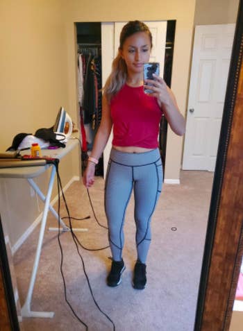 Reviewer wears same style workout crop top in a red shade with gray leggings