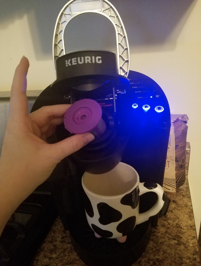 A reviewer putting the purple K cup into the machine 