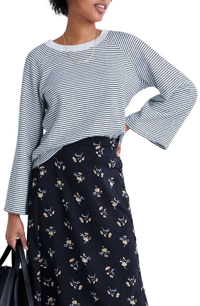 Model wearing Madewell striped terry sweatshirt in blue and white with raglan sleeve paired with a floral skirt