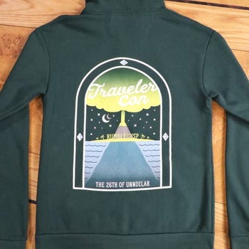 the back of the forest green sweatshirt with a logo for traveler con on it