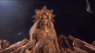 Beyoncé in a regal headpiece with arms reaching out to touch her