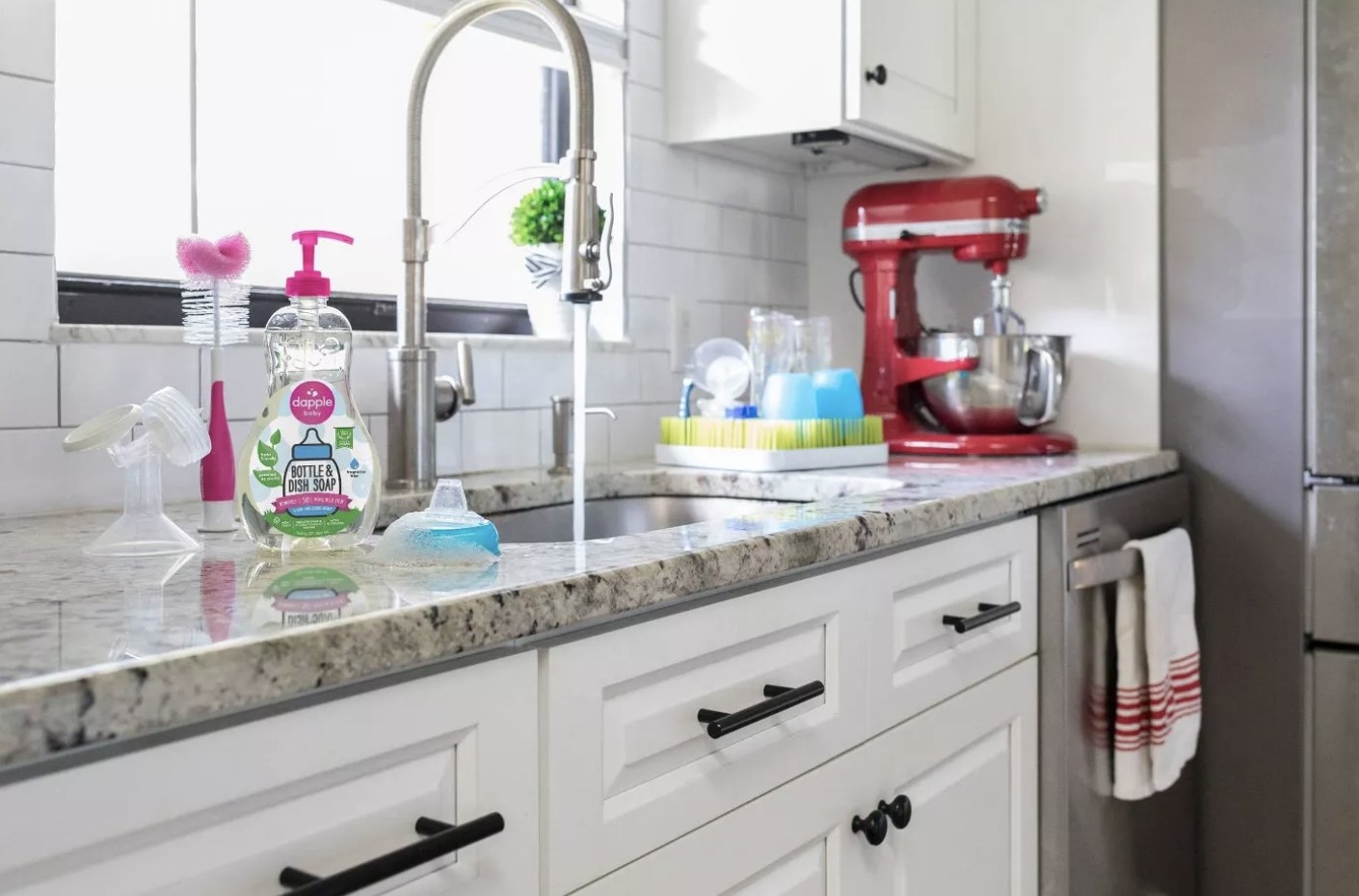 Pink and clear bottle of Dapple Bottle and Dish Soap next to a silver sink