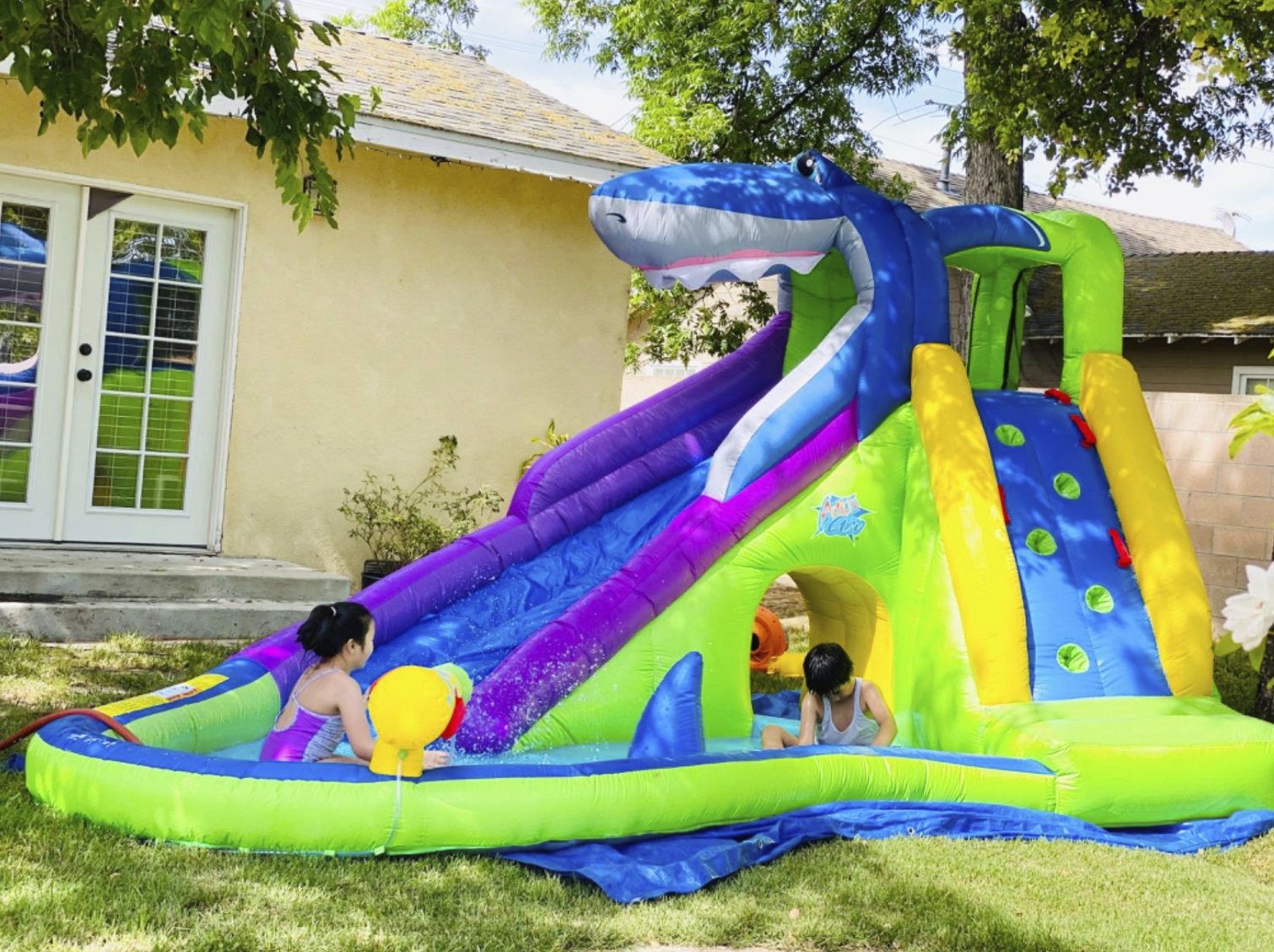 the blow-up slide with has a shark mouth at the top of the slide and a climbing slide on the side with foot rungs for climbing. Both slides have a small sitting area. The two slides are also connected by an open tunnel to crawl through.