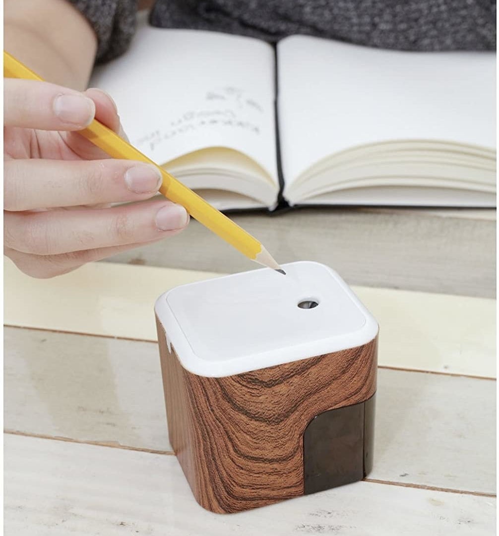 A person putting a pencil into the sharpener