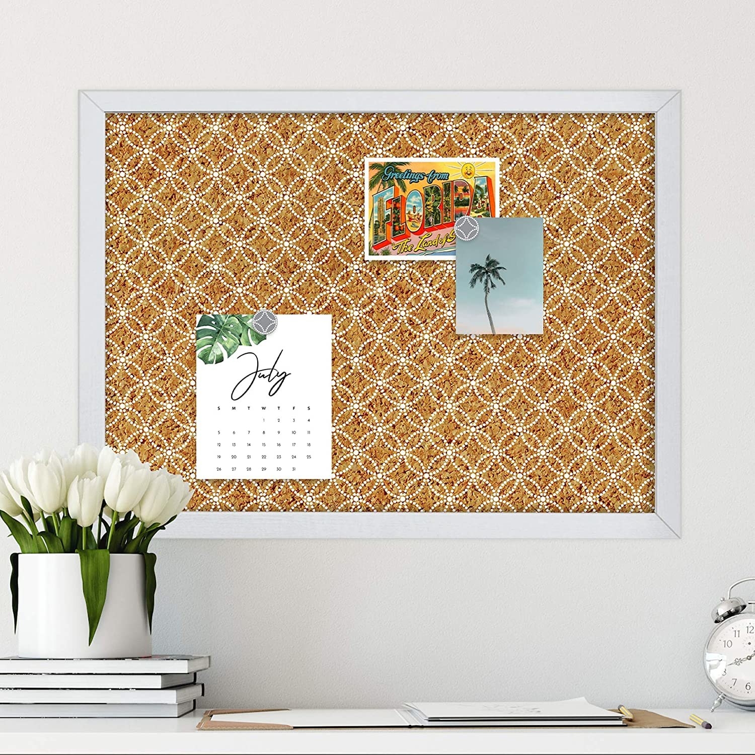 A patterned cork board with postcards and a calendar on it