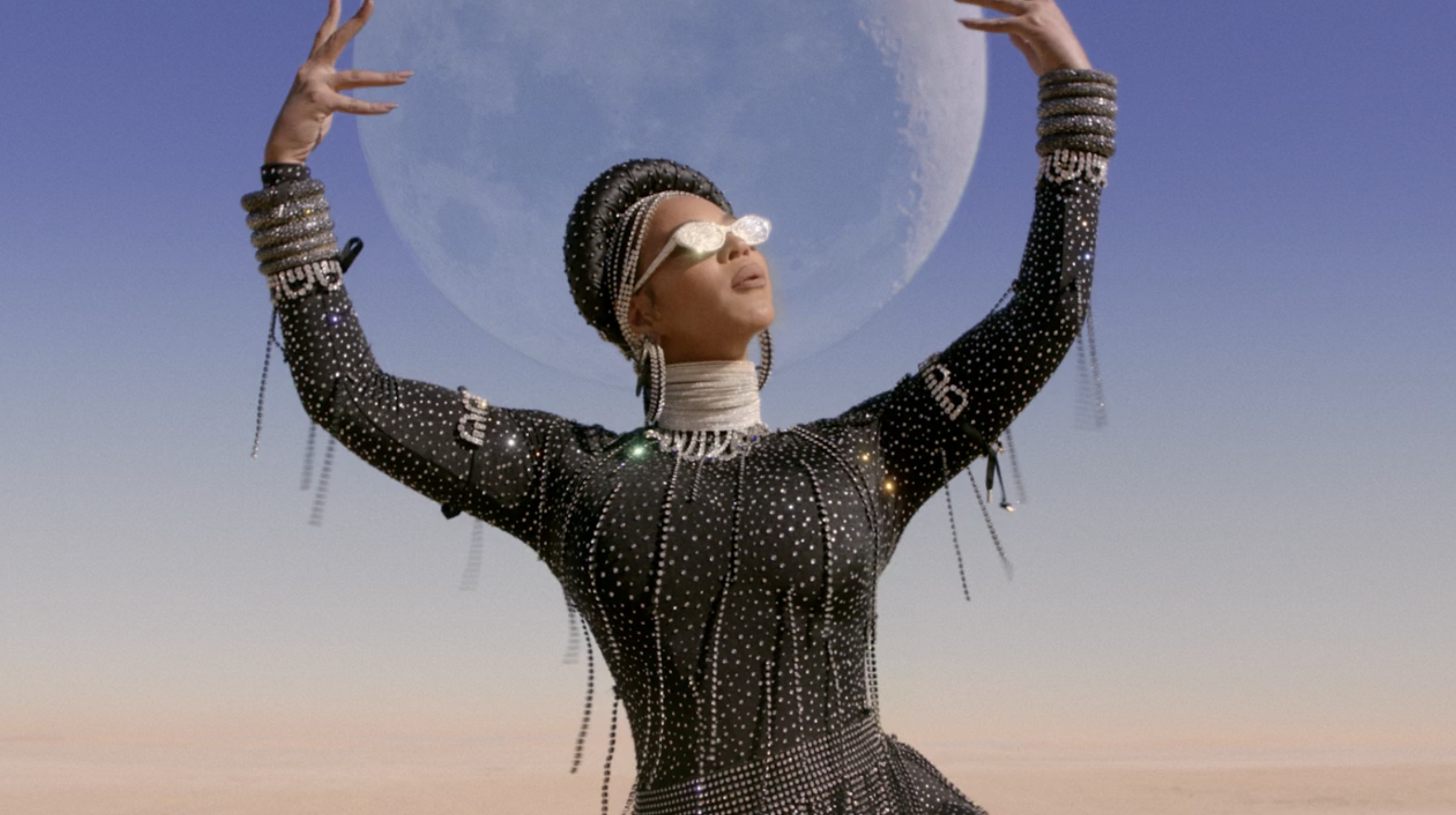 Beyoncé holding up her arms with the moon behind her