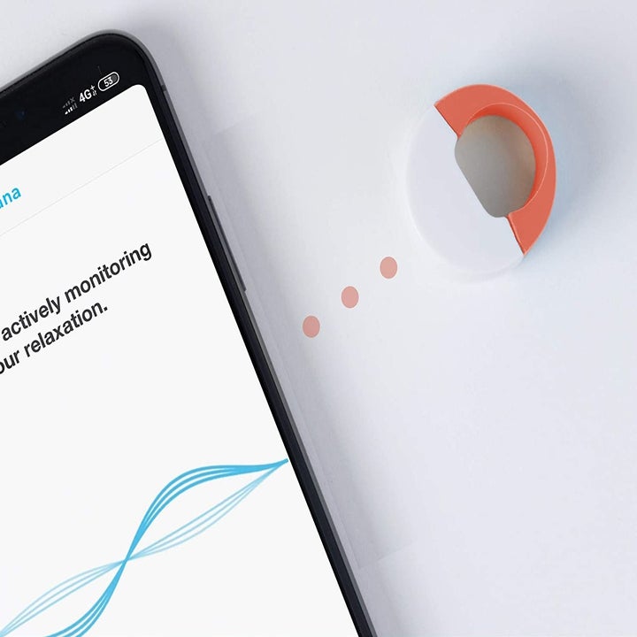 The ring pictured next to a mobile phone with the Dhyana app on it.