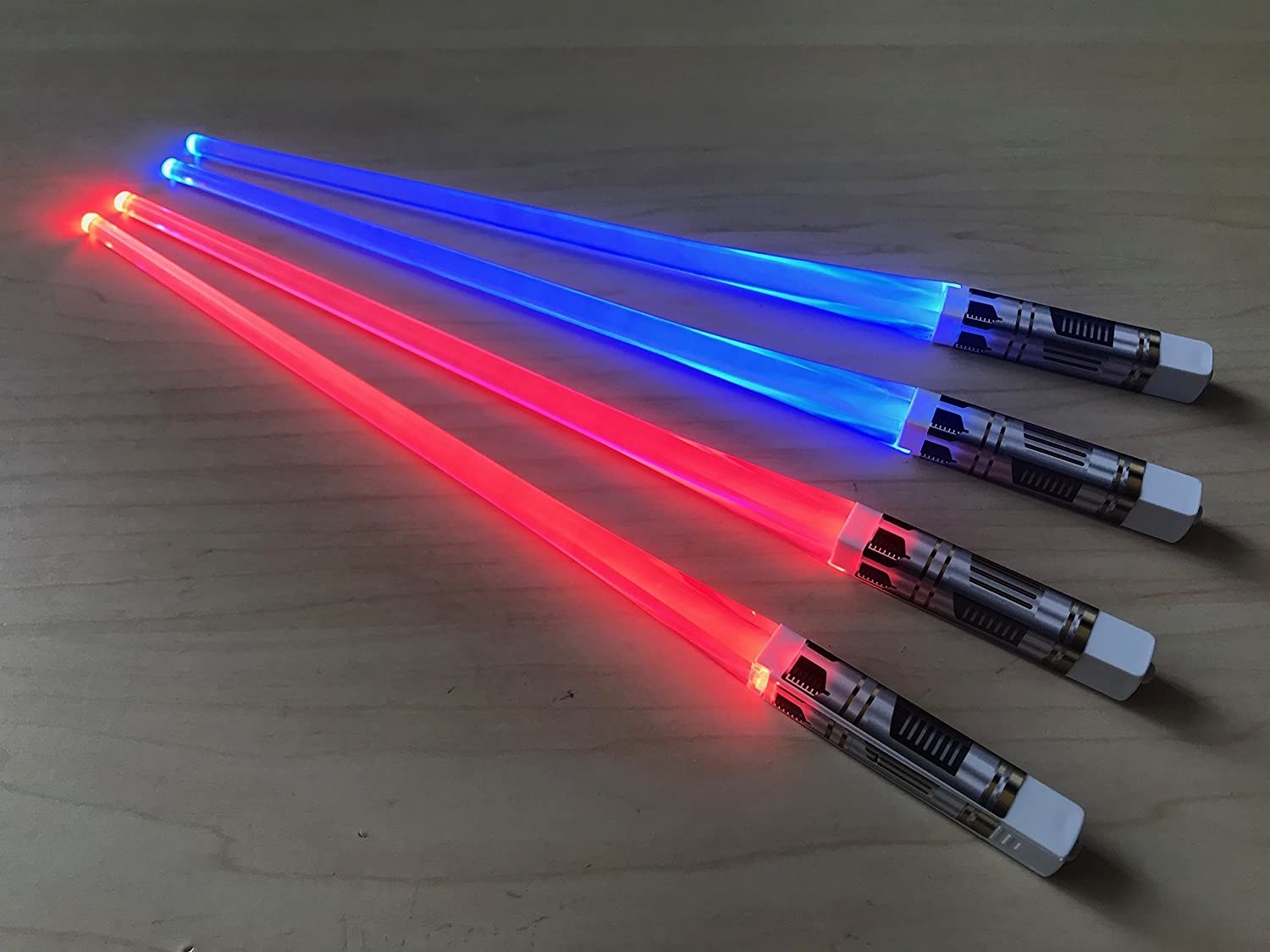 Two pairs of lightsaber chopsticks on a wooden table