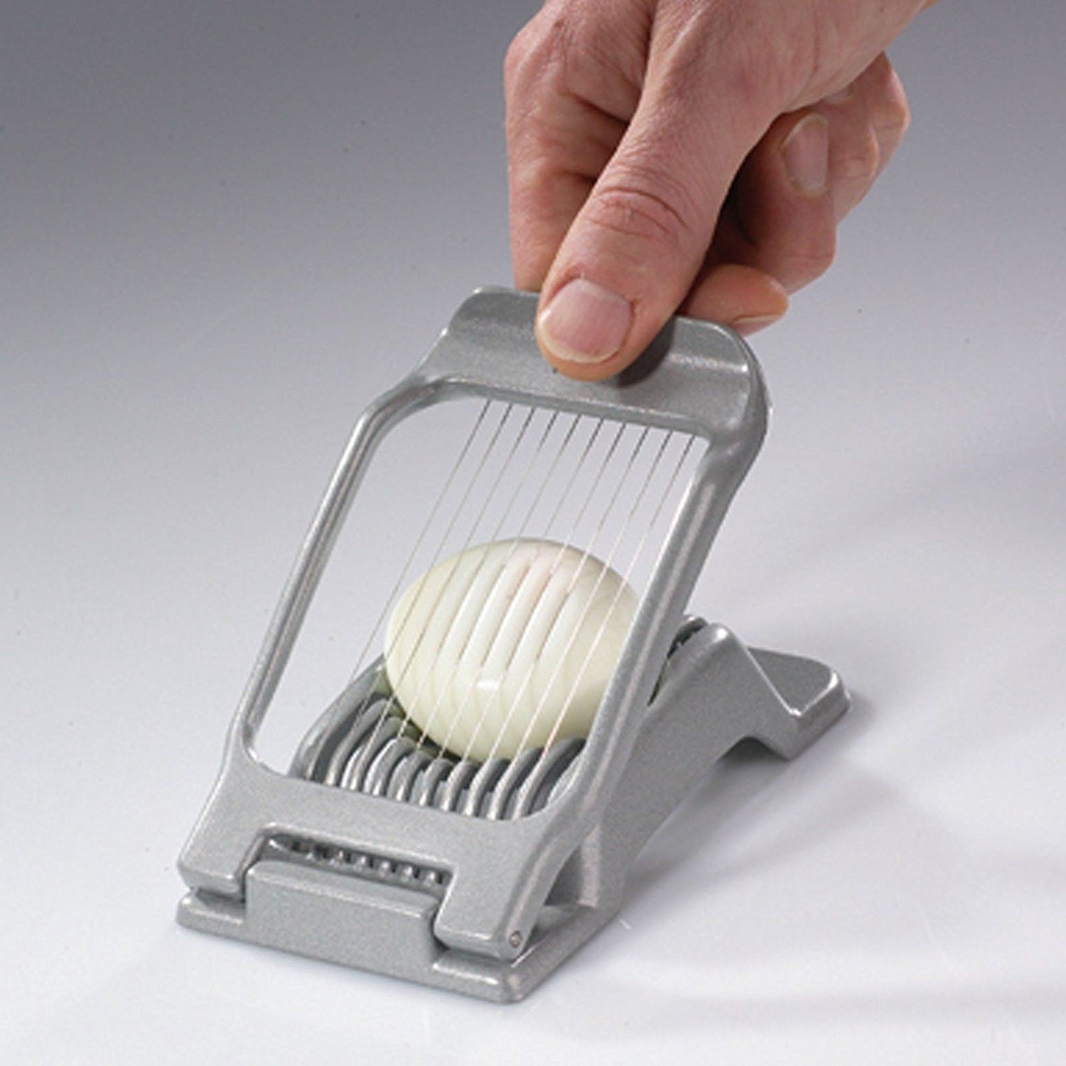 A person presses the egg slicer into a hard boiled egg