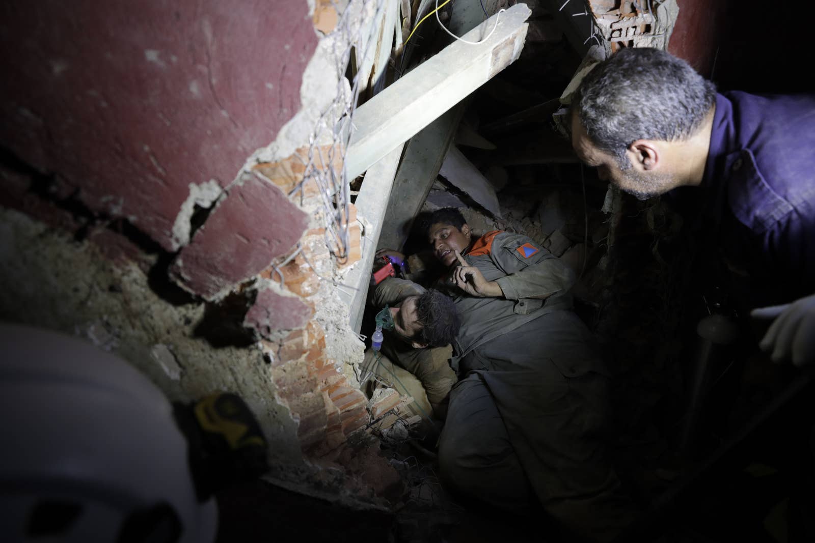 Two soldiers search in a destroyed house for survivors with a flashlight at night