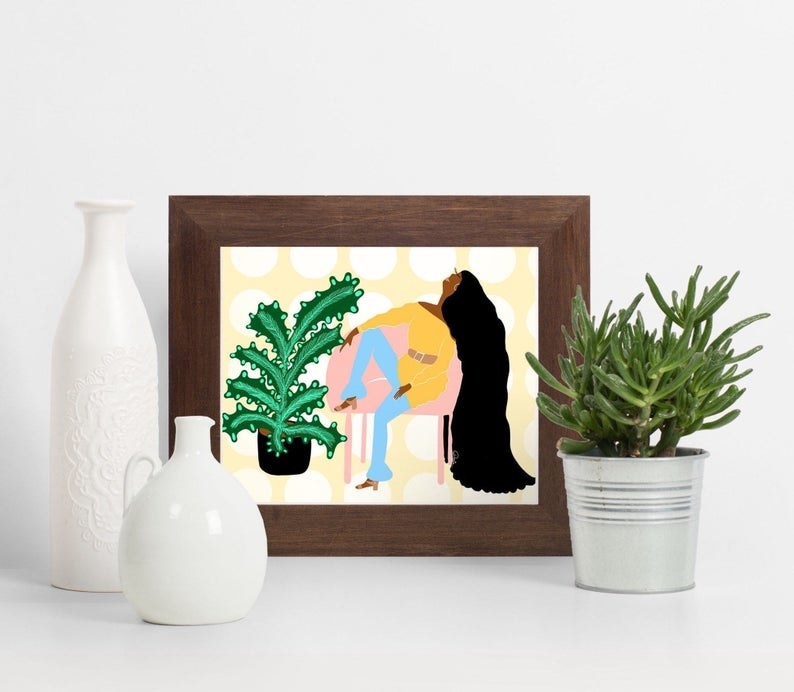 framed illustration of black person with long hair sitting on a chair with a plant beside of it