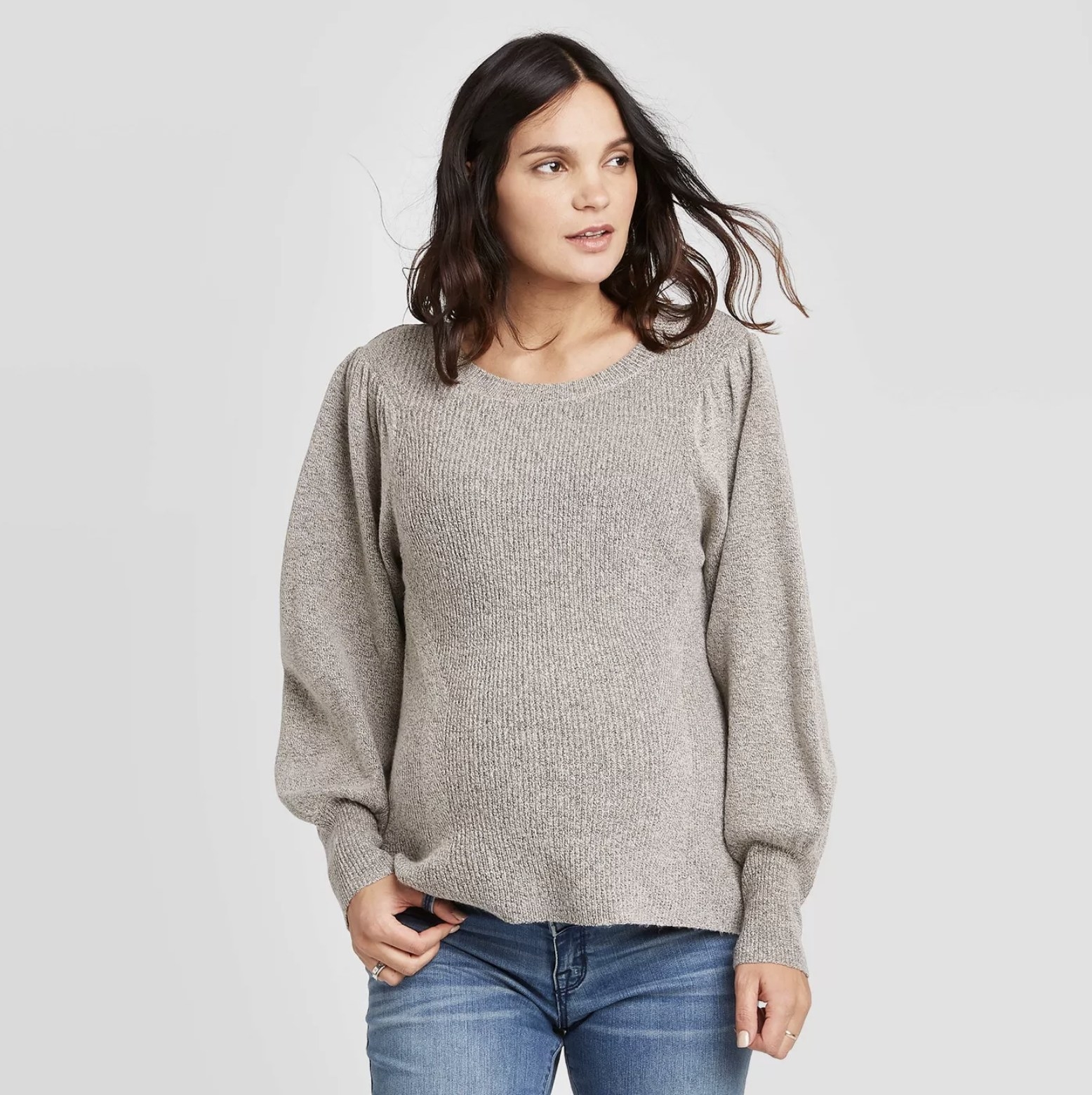 Model wears gray maternity sweater with dark blue jeans