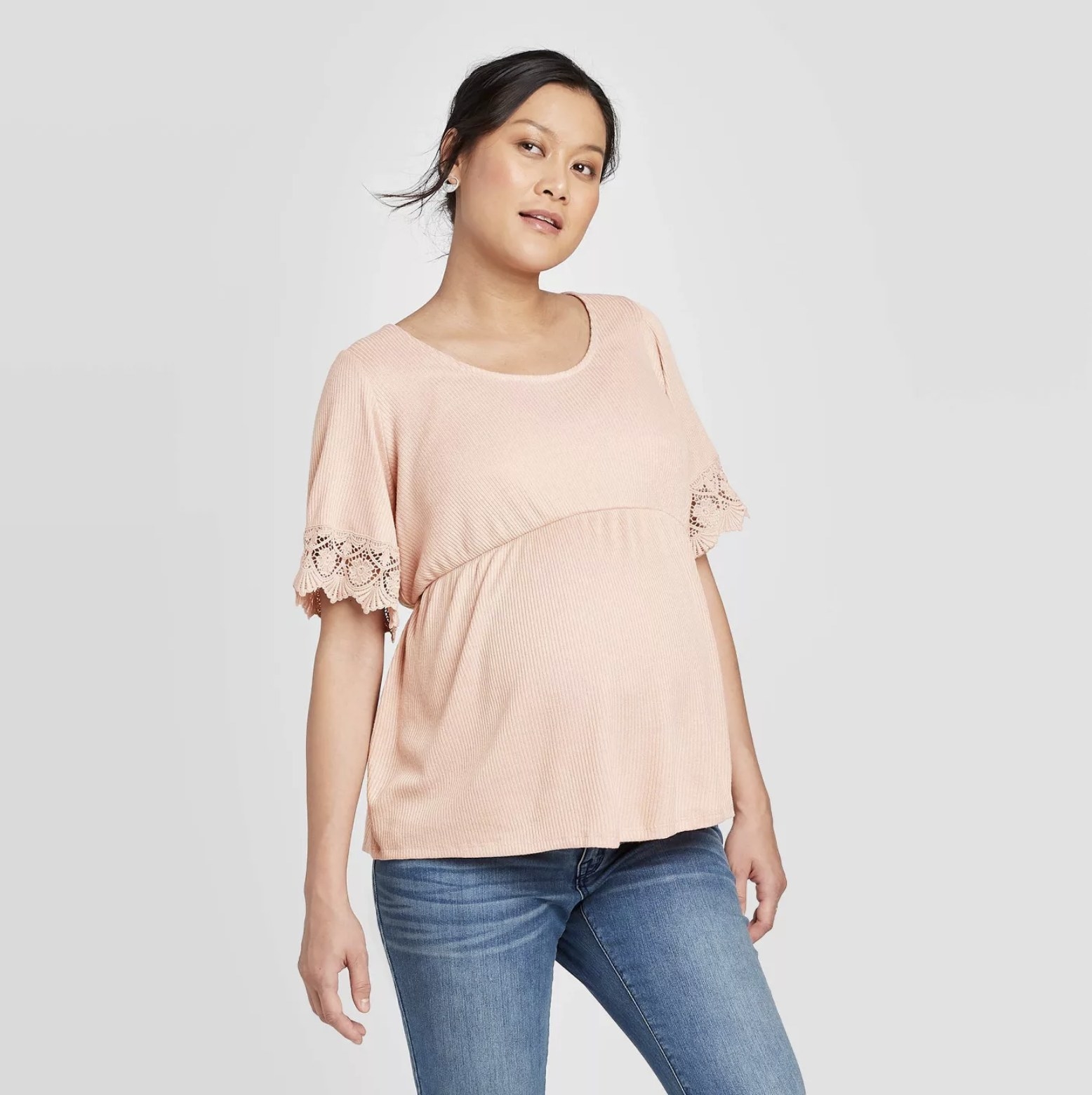 Model wears light pink short-sleeve ruffle top with blue jeans