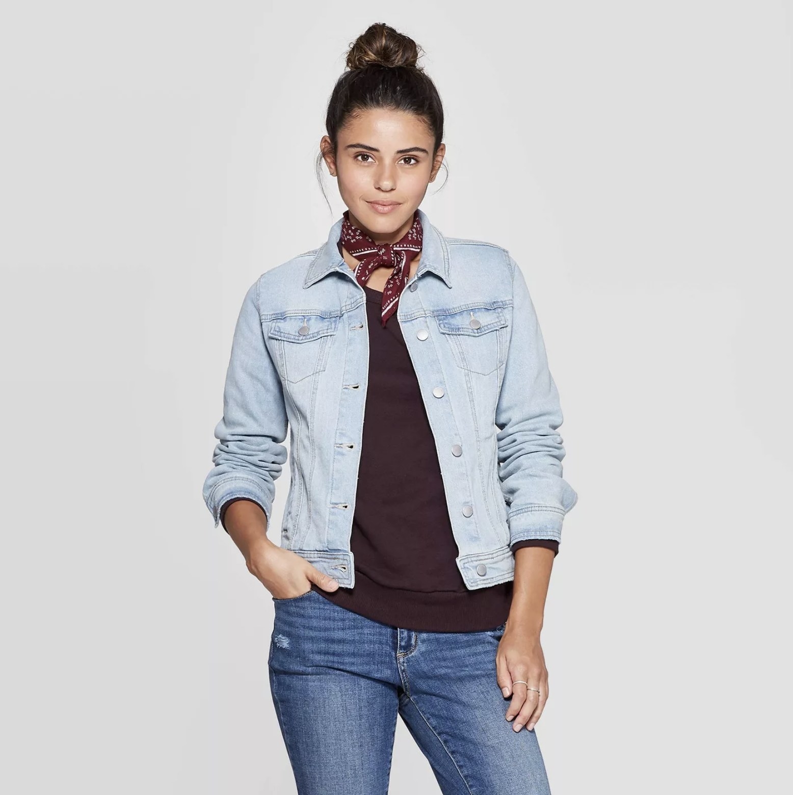 Model wears light blue denim jacket with maroon top and medium blue jeans
