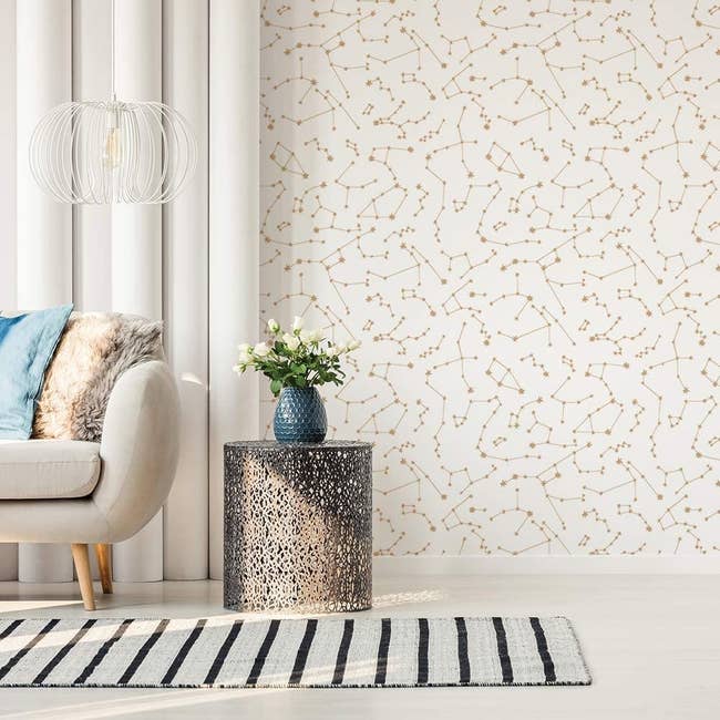 A living room with one wall covered in the constellation-print wallpaper in Frost