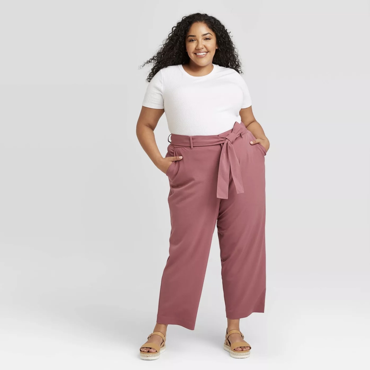 Model wears pink tie-waist straight pants with a white top