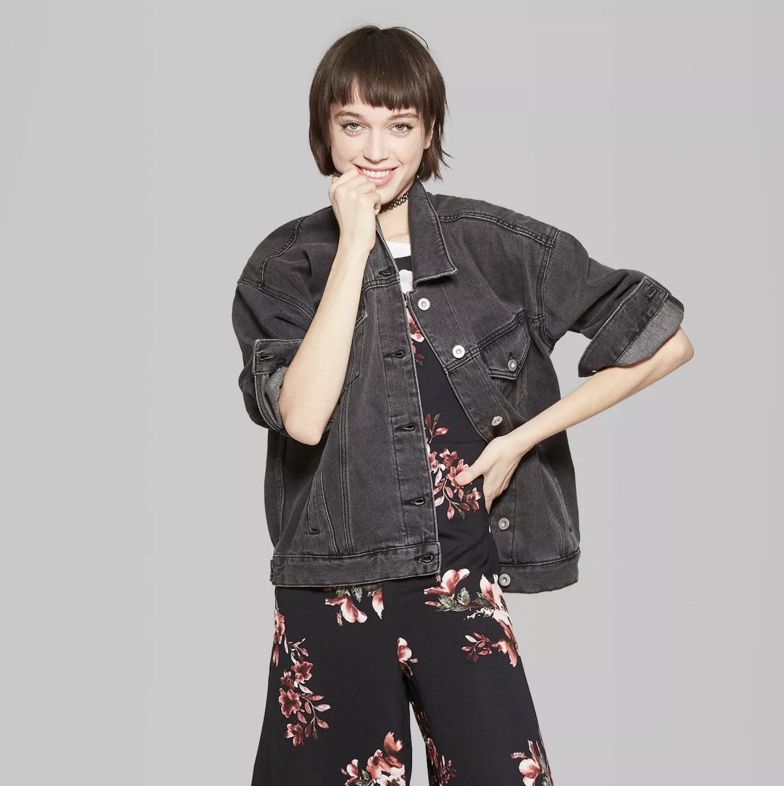 Model wears light black denim jacket over floral jumpsuit