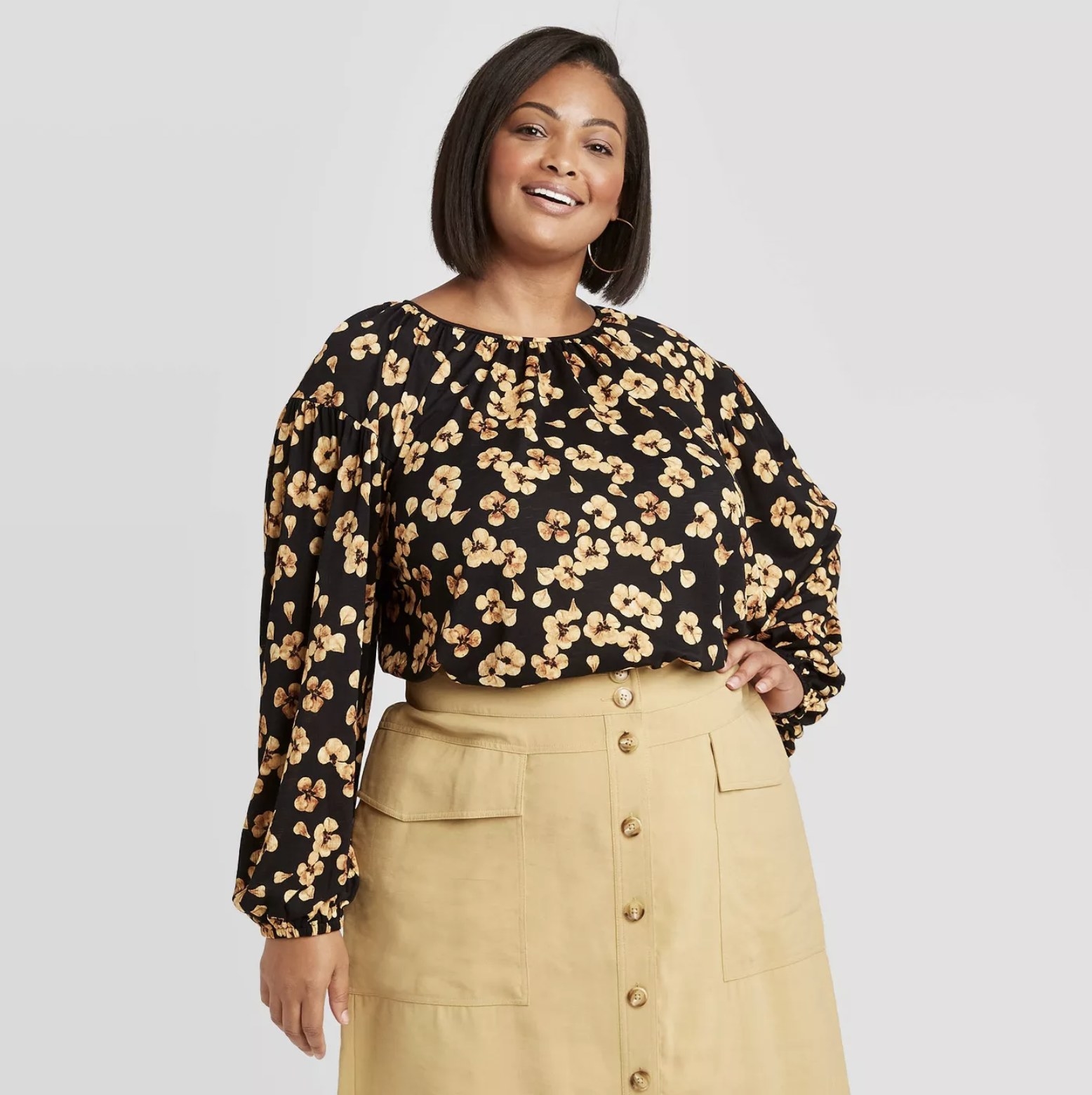 Model wears floral-print blouse with a khaki skirt