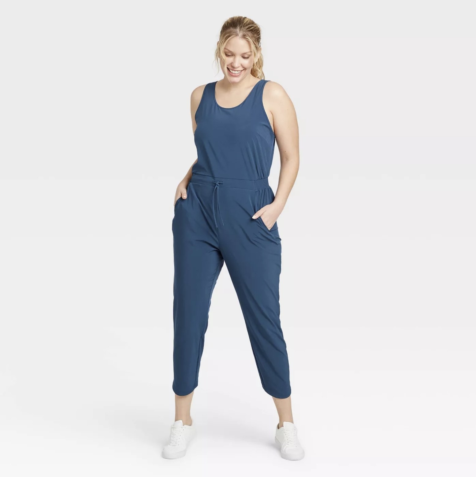 Model wears light blue stretchy woven jumpsuit with white sneakers
