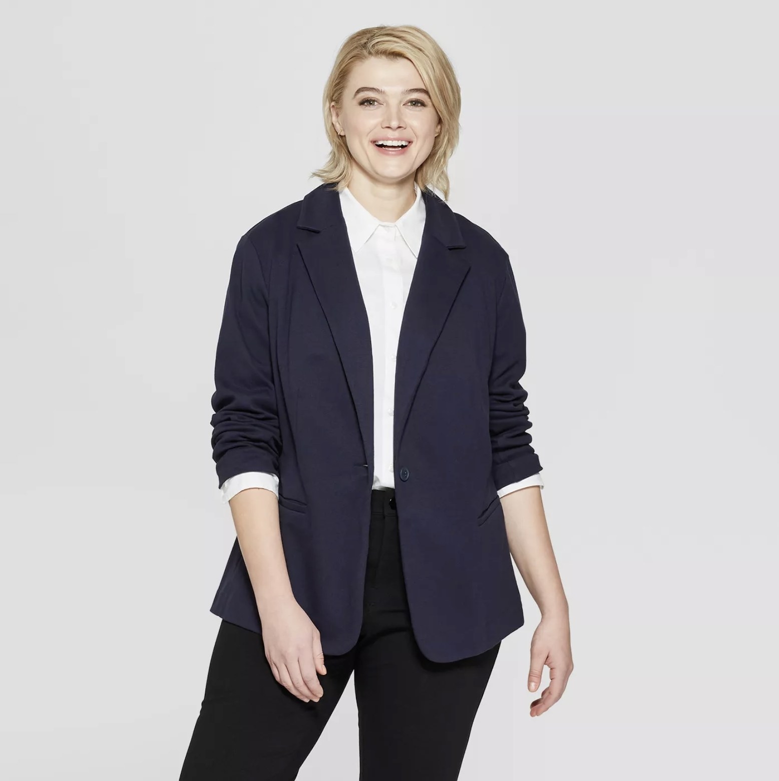 Model wears a navy knit blazer with a white collared shirt and black skinnies