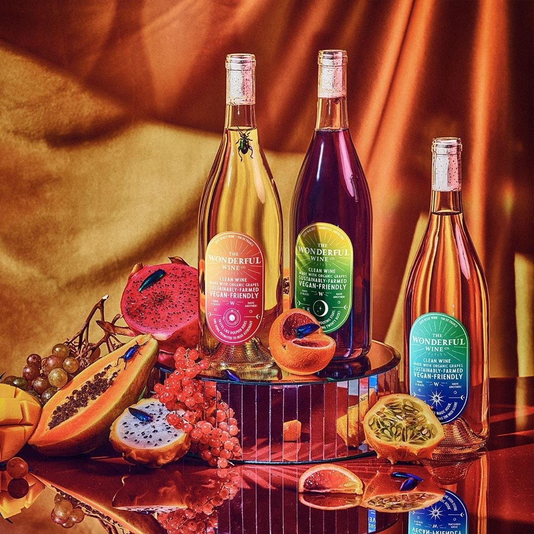 three bottles with gradient labels shown next to fruit 