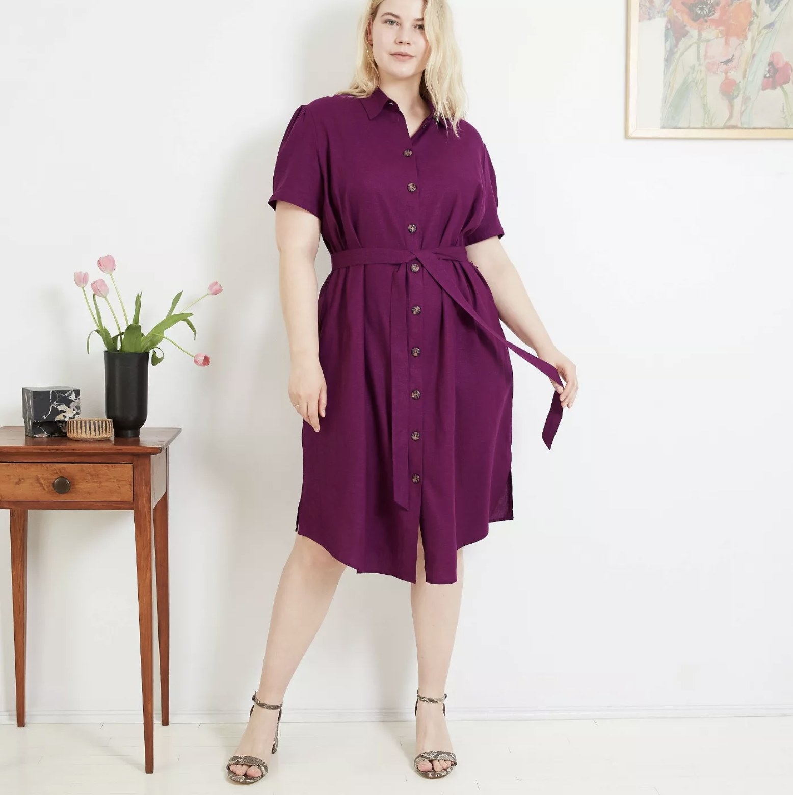 Model wears purple short-sleeve dress with buttons and a tie waist