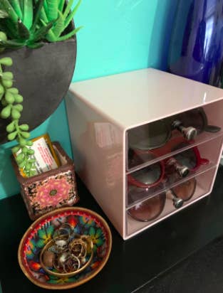 Reviewer pic of the pink organizer with sunglasses inside on a vanity