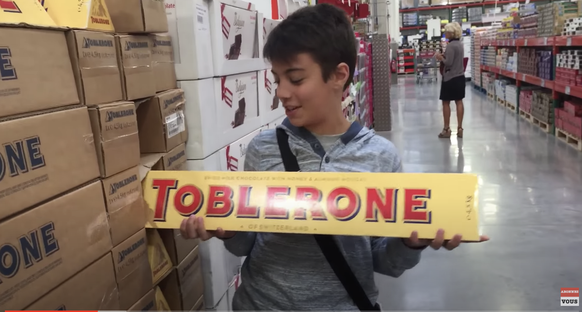 A young boy proudly holding an extremely large bar of Toblerone chocolate
