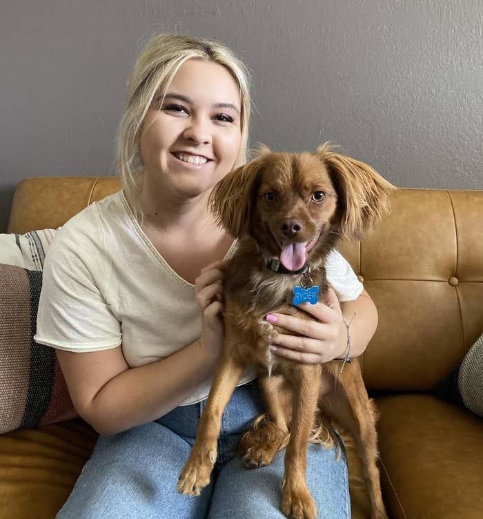 A smiling woman holds a happy dog in her lap